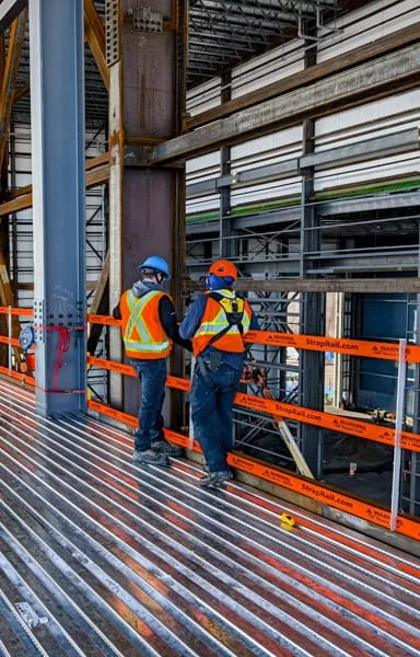 StrapRail protects workers at the edge of a large steel building.